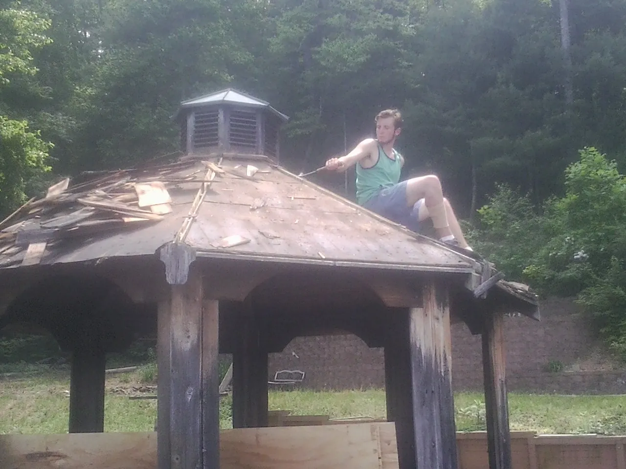 Tearing the old roof off a wooden gazebo before new shakes in Epping
