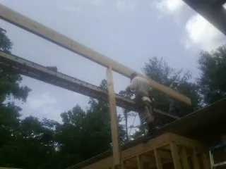 Carpenter setting a ridge beam over a new addition frame — Ice Dam Removal by Roofing Brothers in Epping