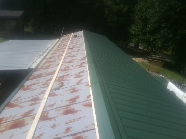 Old rusted panels beside newly installed green metal roofing — Wind Damage Roof Repair by Roofing Brothers in Epping