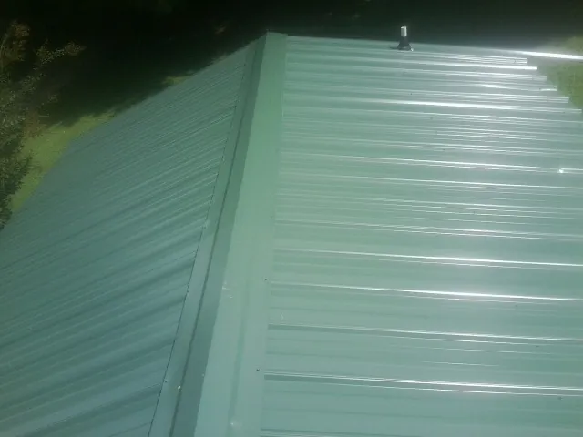 New green metal panels meeting at the ridge of a roof — Flat Roof Repair work by our crew in Epping
