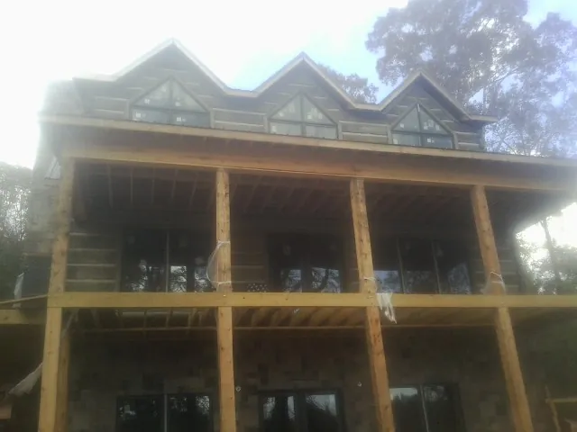 Dormers and porch framing on a large log home under construction — Roof Coating work by our crew in Epping