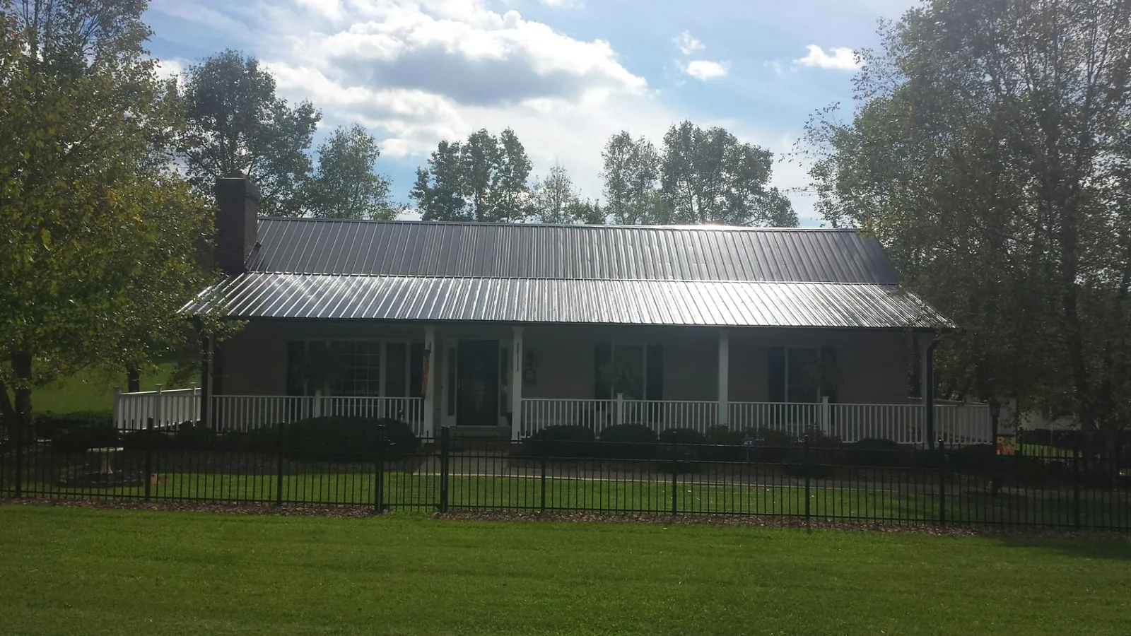 Gray metal roof on a brick ranch with a full width front porch — Gutter Guard Installation work by our crew in Epping