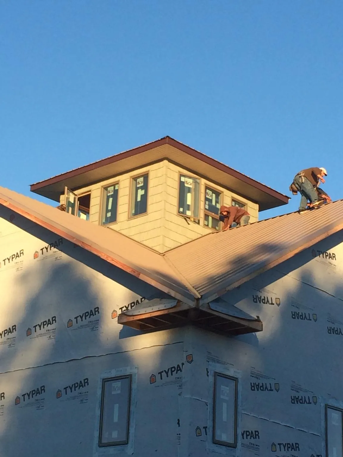Roofers working around a rooftop cupola on a new metal roof at sunset — Roof Waterproofing in Epping by Roofing Brothers
